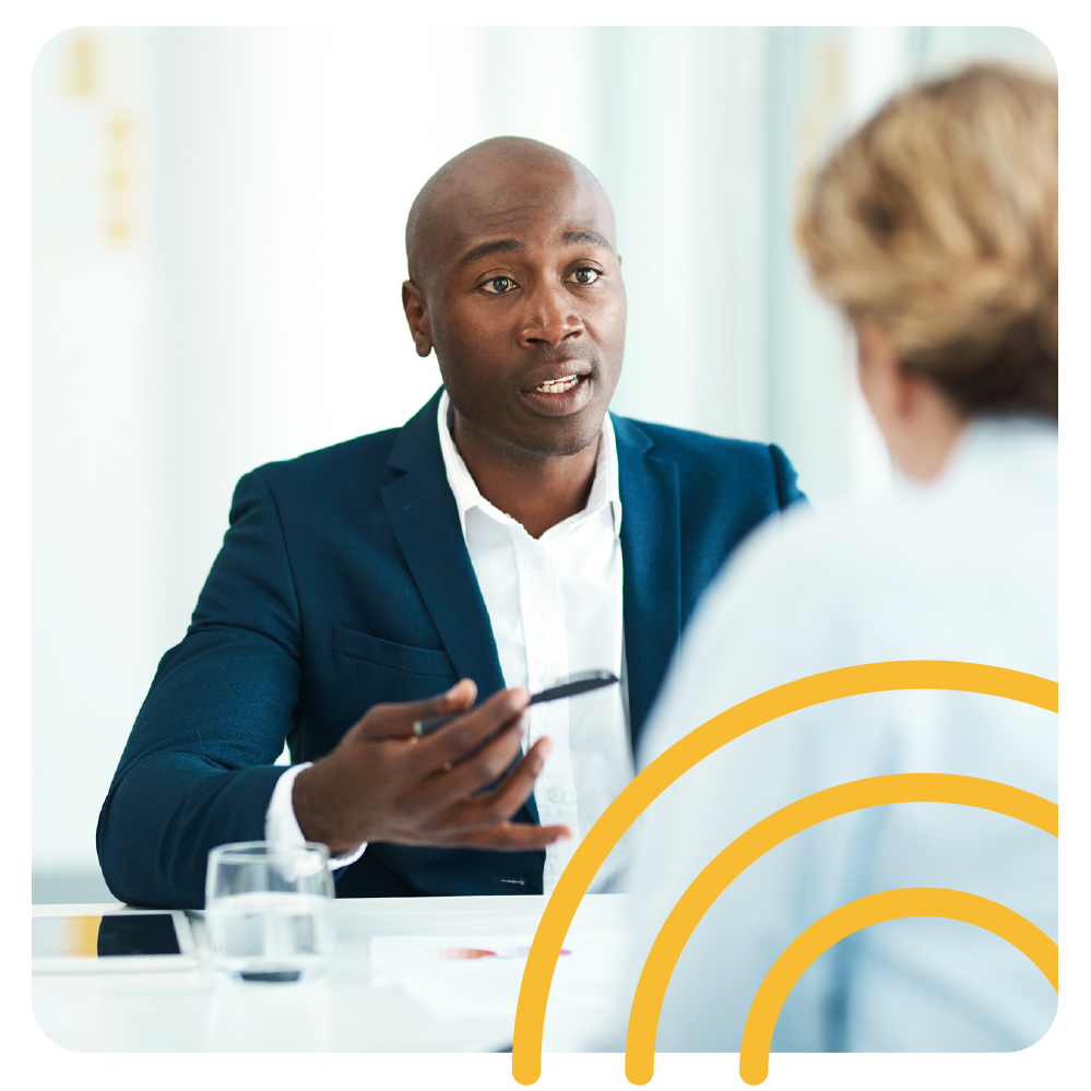 a man in a suit is sitting at a table talking to a woman .