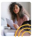 a woman is sitting at a table reading a piece of paper .