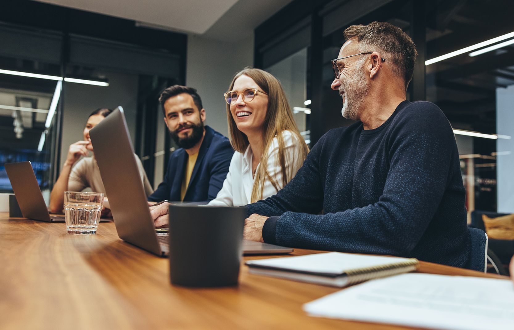 a group of people are sitting at a table with laptops on a crm system.