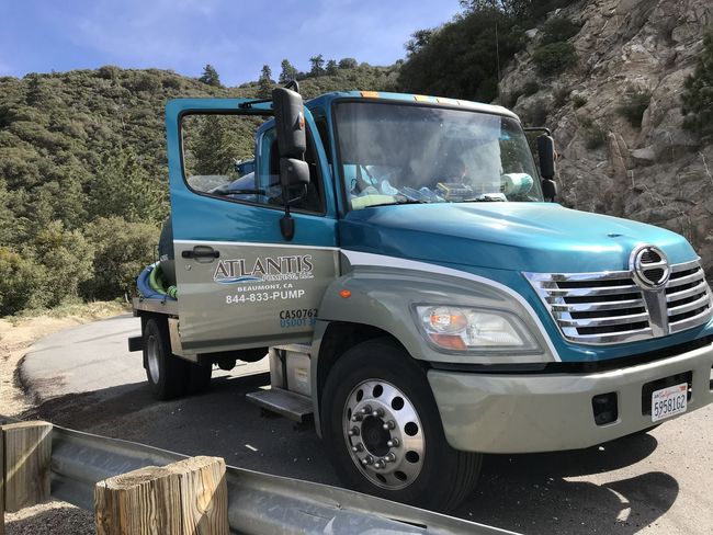 Blue utility truck parked on a mountain road with driver door open