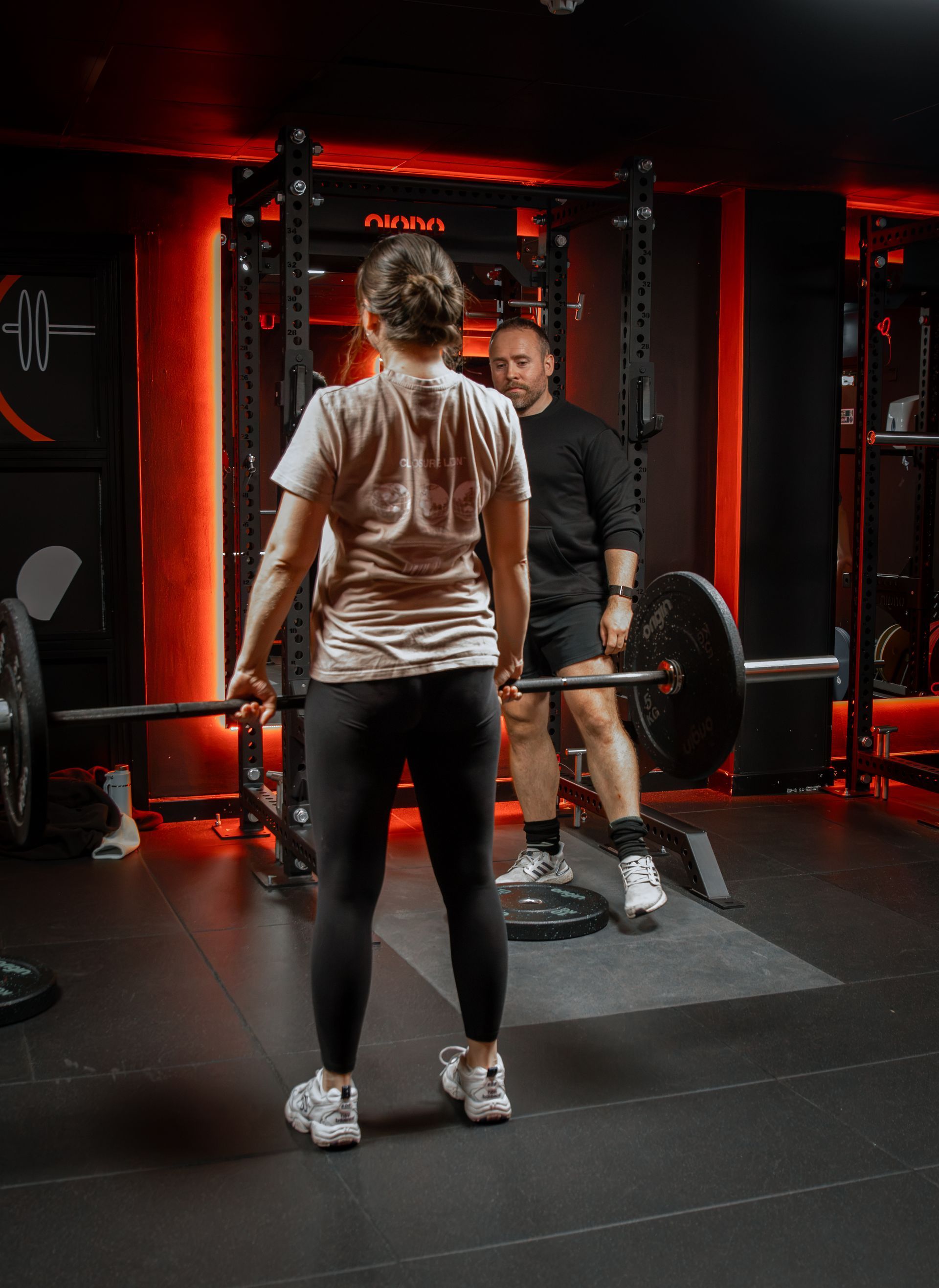 Personal trainer coaching a member on a barbell lift at Fervid Fitness