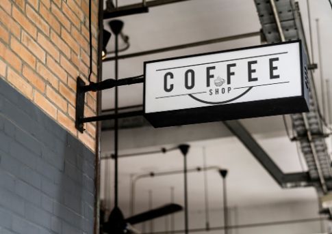 A Coffee Shop Sign Is Hanging from A Brick Wall — Brookes Engraving & Signs in Wollongong, NSW