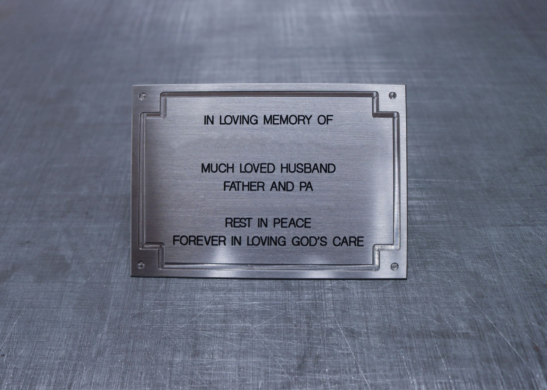 A metal plaque that says in loving memory of much loved husband father and pa rest in peace forever in loving god 's care 