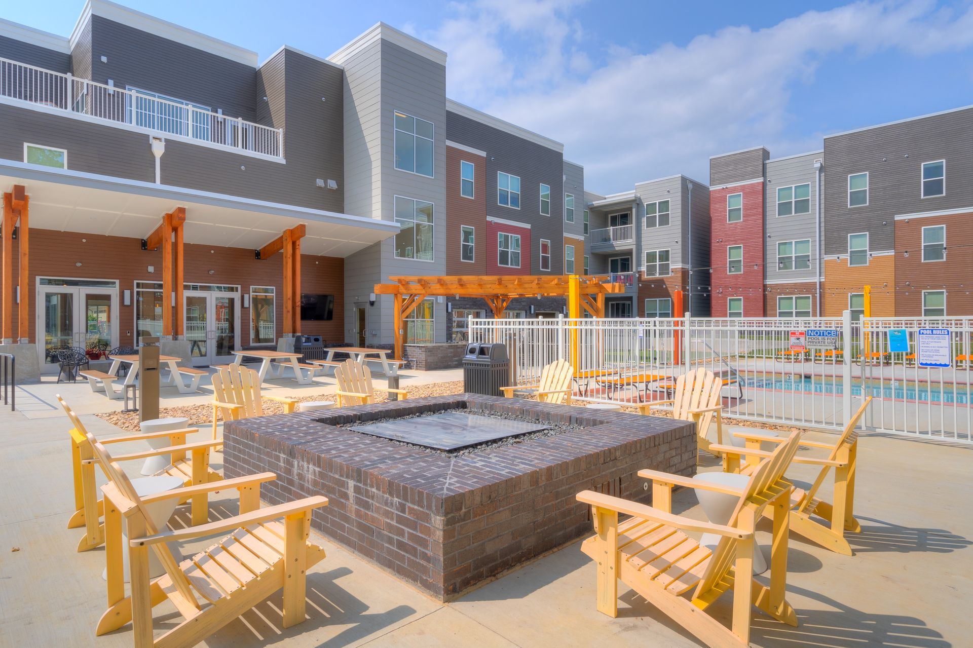 Outdoor apartment complex patio with a fire pit, seating, and pool.