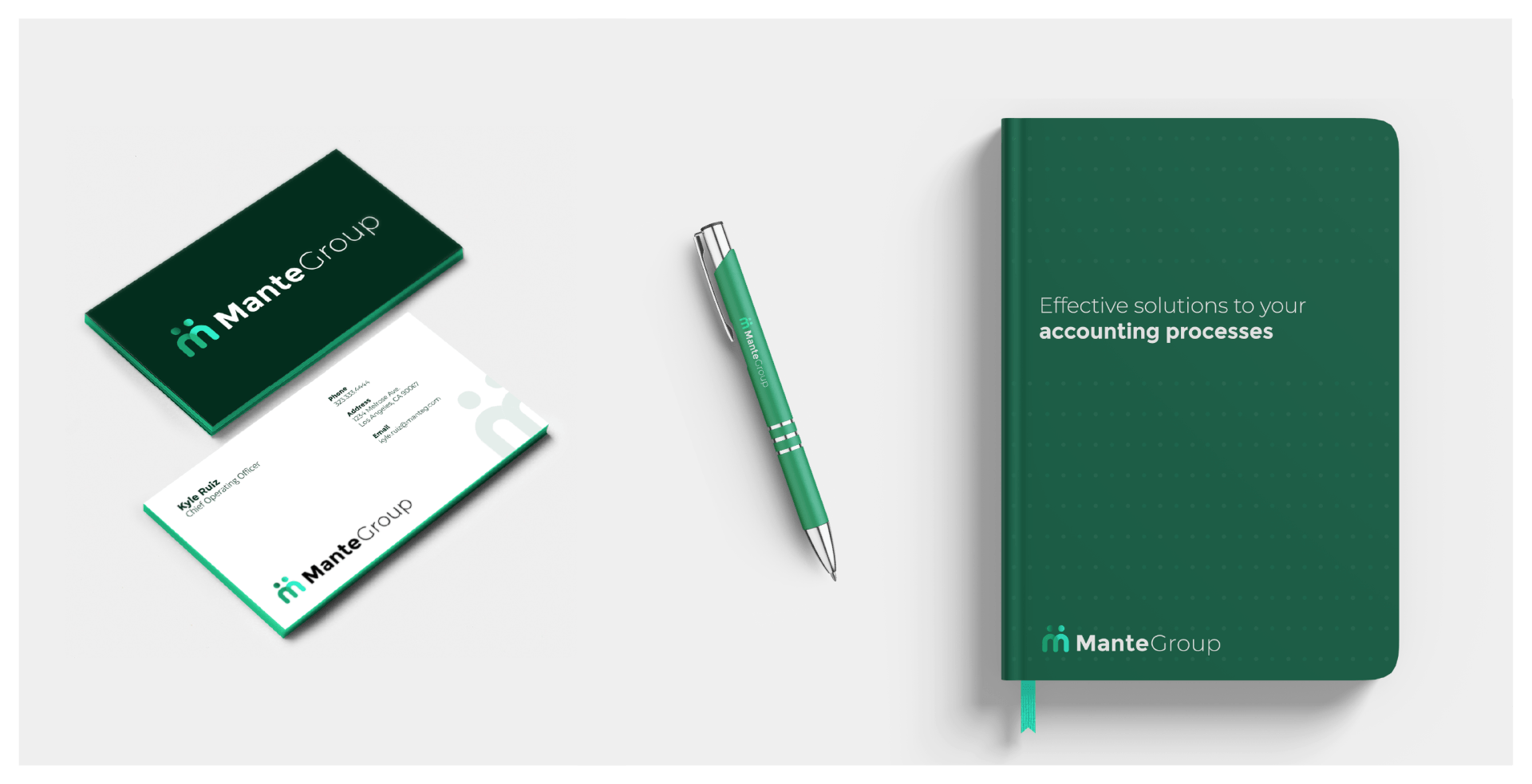 A dark green branded notebook, matching pen, and business cards with a green and white Manta Group logo on a white surface.