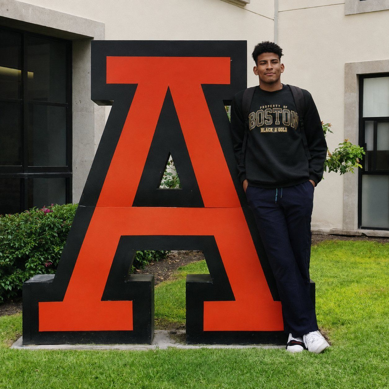 Young athlete beside a large school emblem