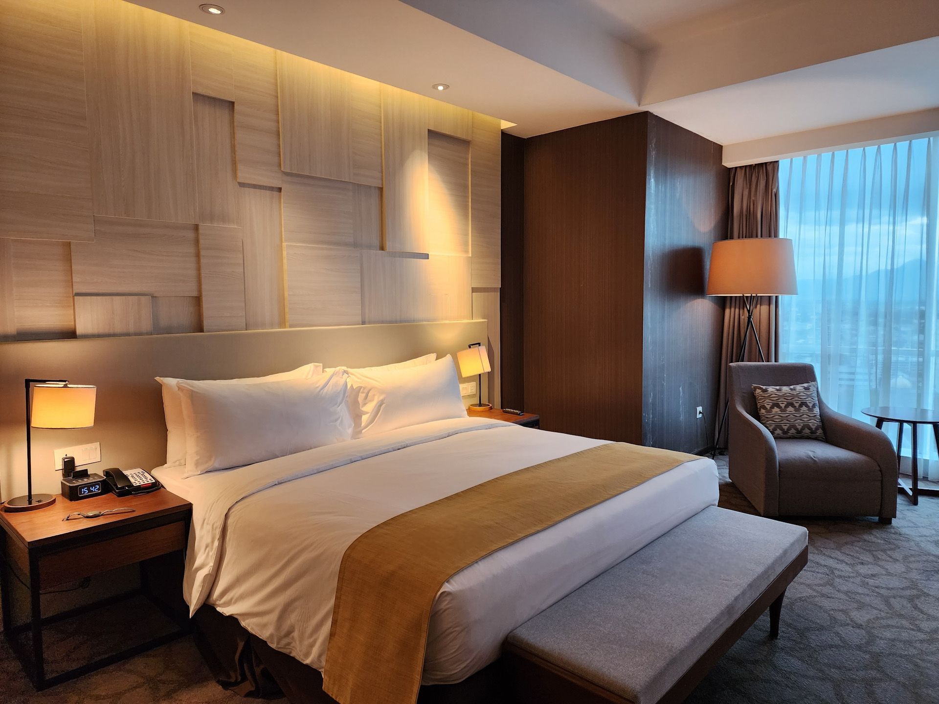 A hotel room with a large bed and a chair