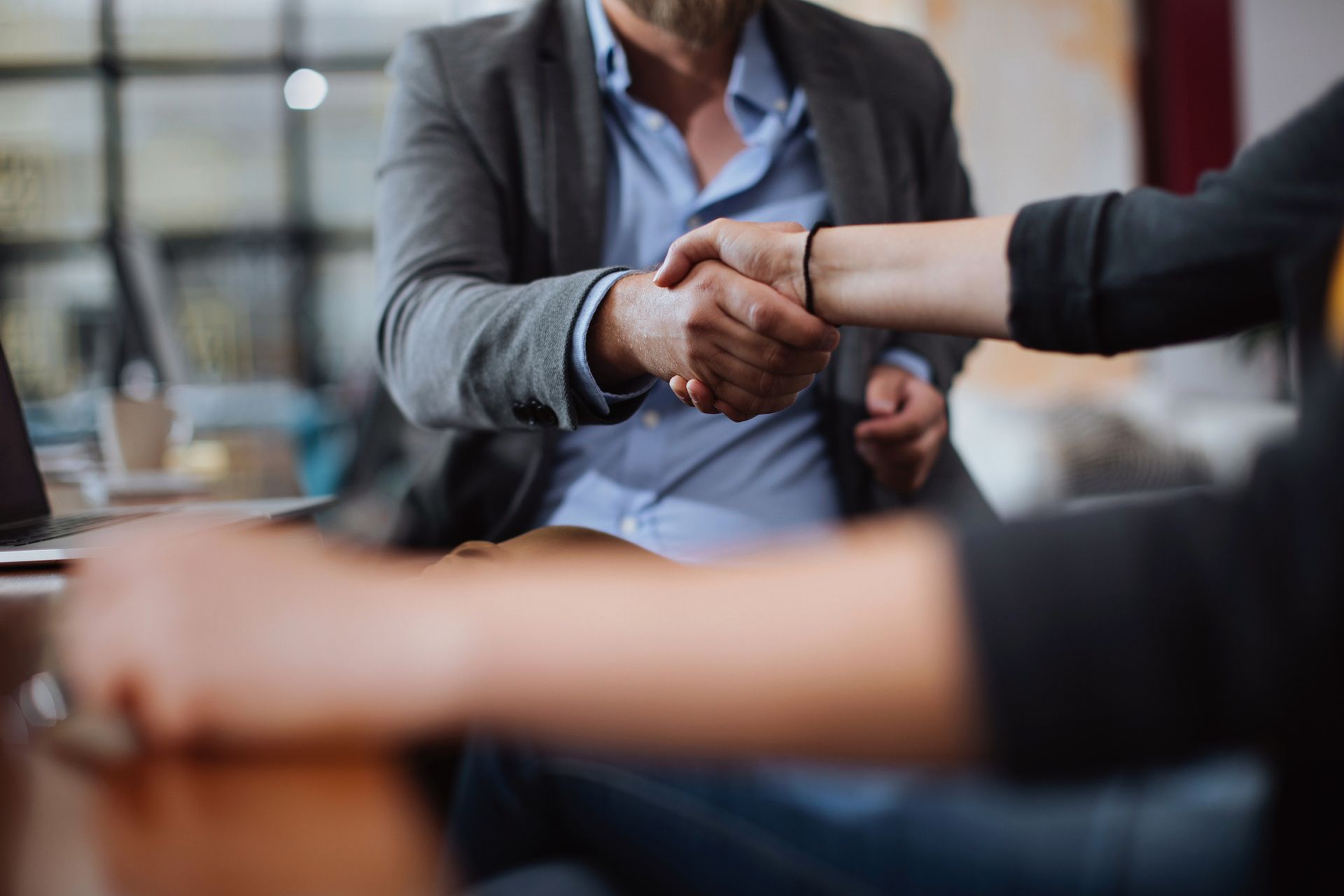 Two people shaking hands in an office setting, symbolizing agreement or business deal.
