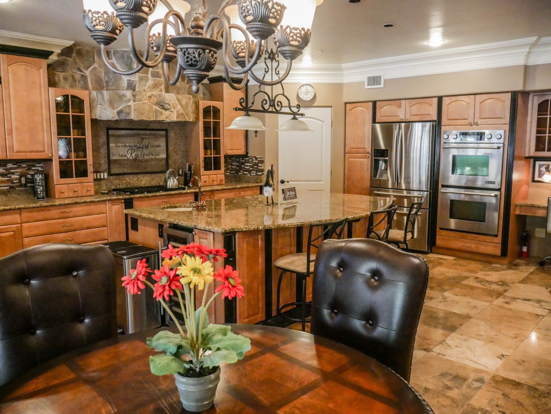 A kitchen with a table and chairs and a vase of flowers on the table.
