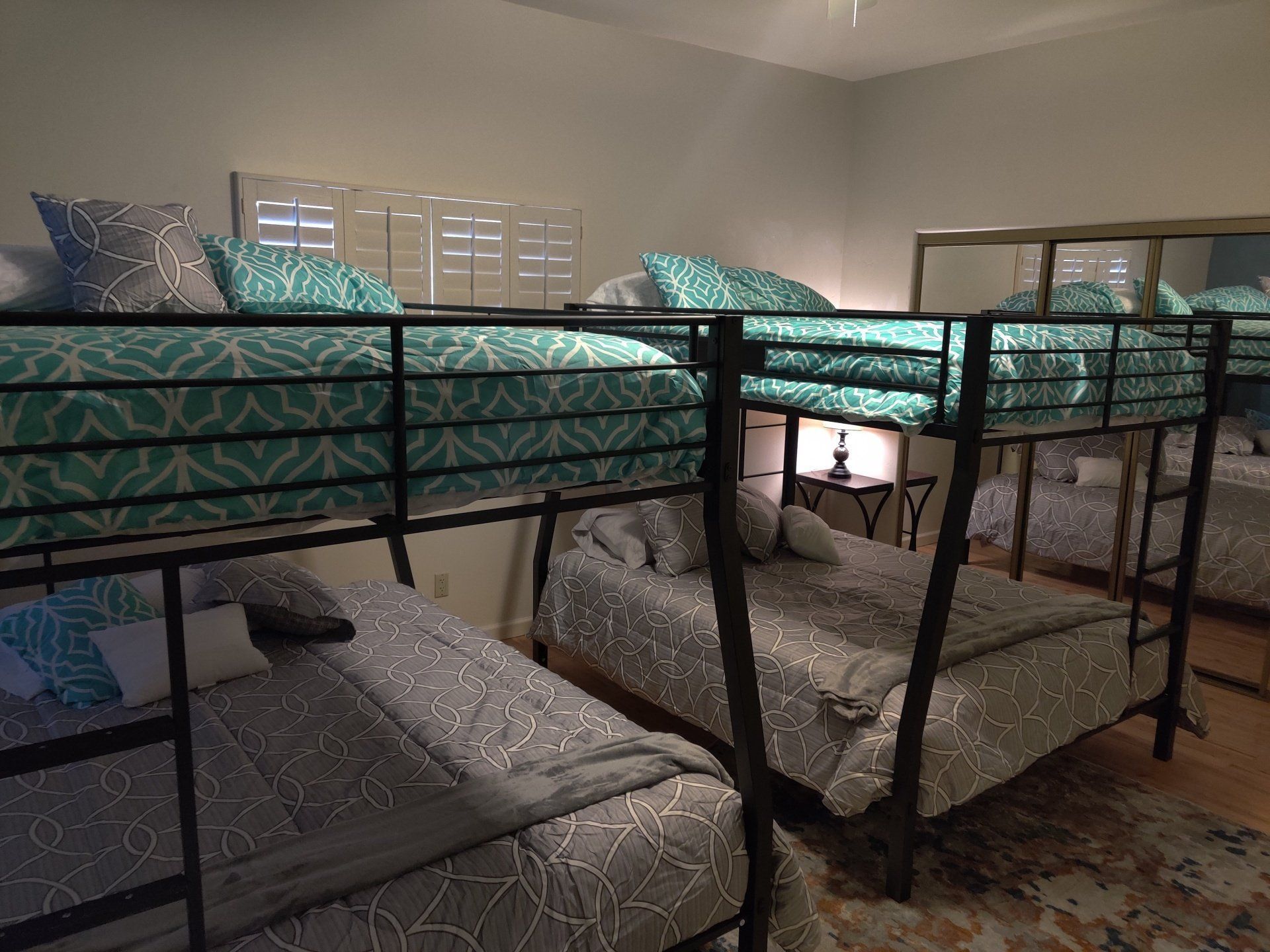 Two metal bunk beds with teal bedding in a bright bedroom