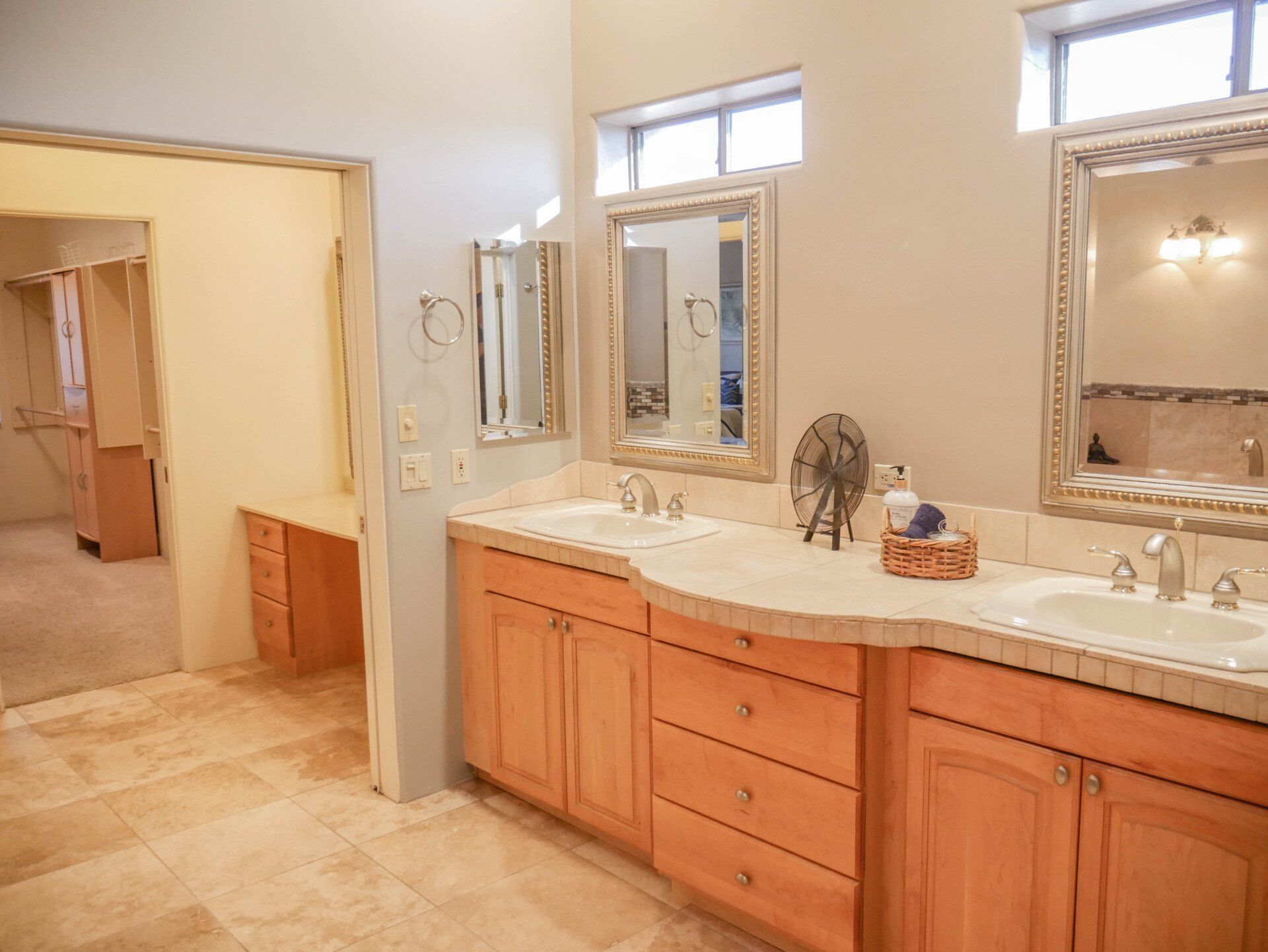 A bathroom with two sinks , two mirrors , and wooden cabinets.