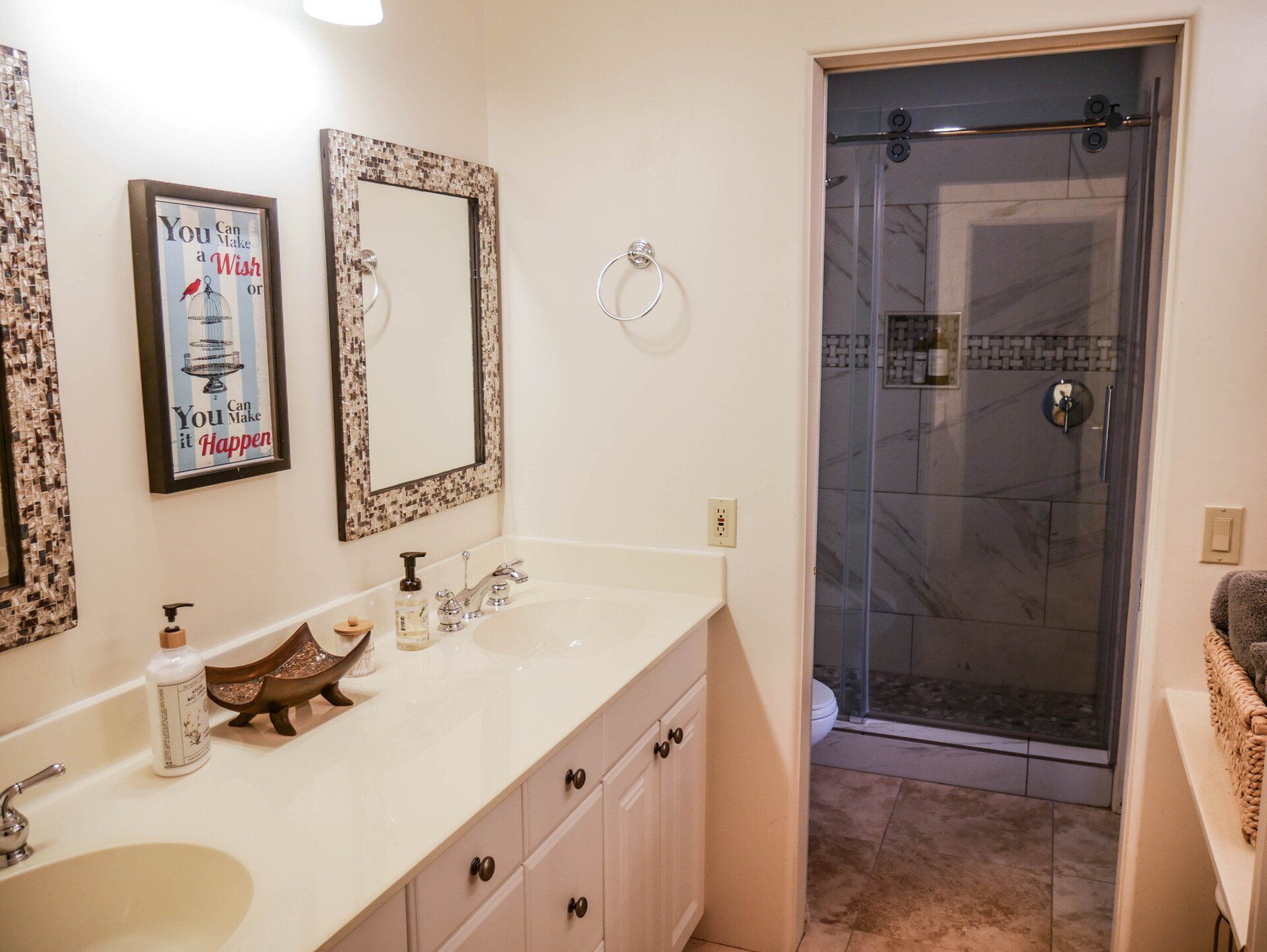 A bathroom with two sinks , a mirror and a walk in shower.