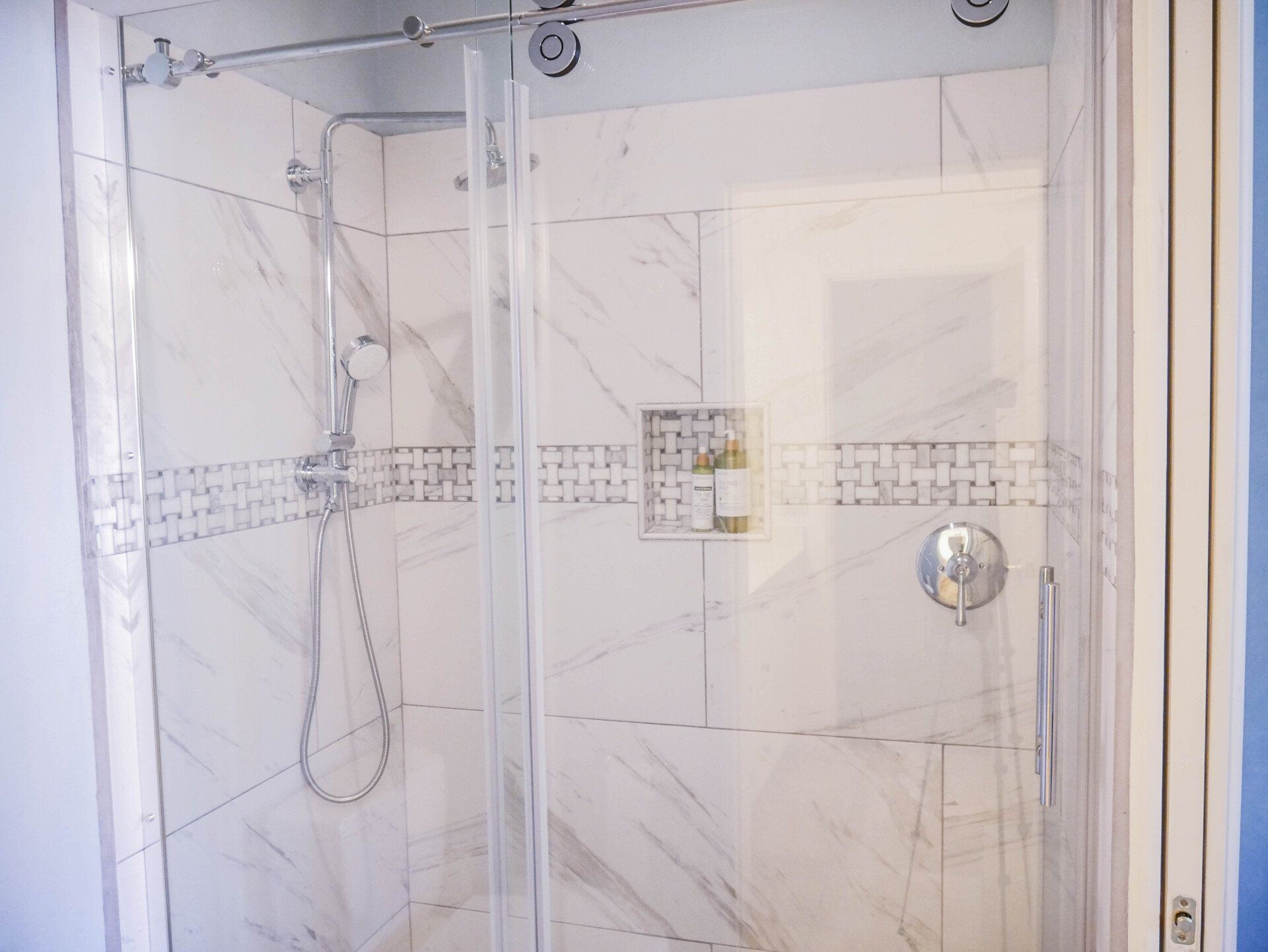 A bathroom with a walk in shower with a glass door.