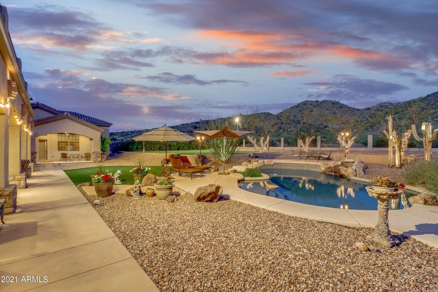 Backyard pool and patio at dusk with desert landscaping and mountain view