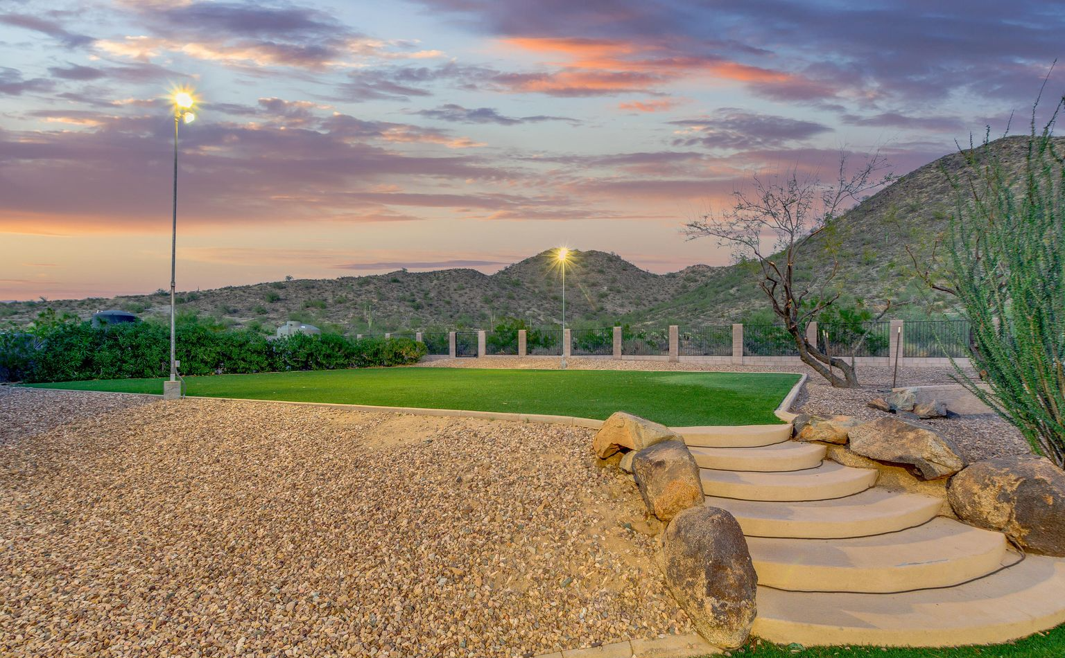 A staircase leading up to a grassy field with a mountain in the background.