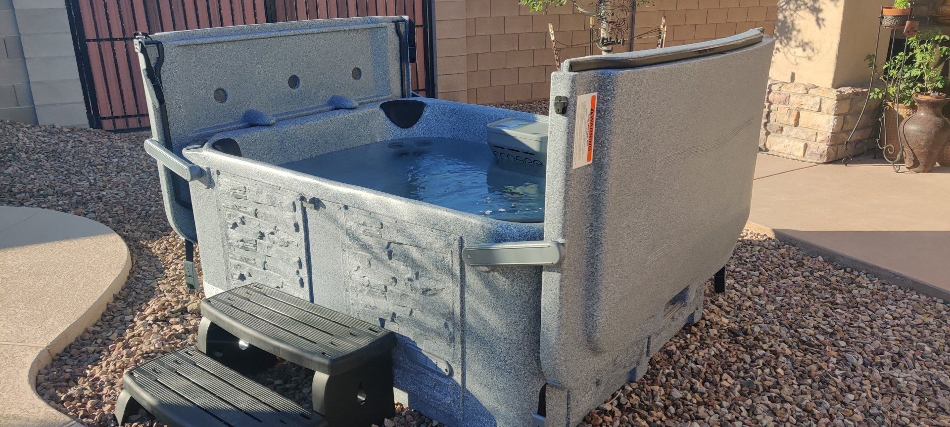 A hot tub with stairs leading up to it is sitting in the backyard of a house.