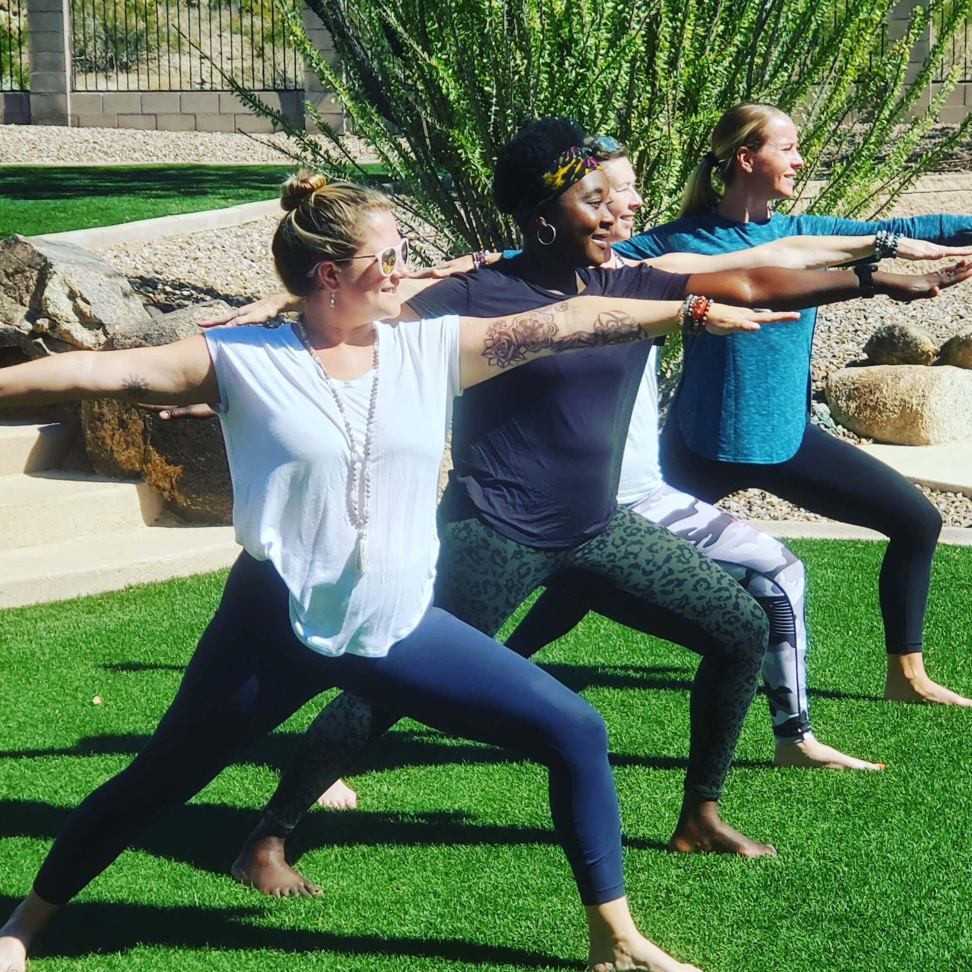 A group of women are practicing yoga on a lush green field.