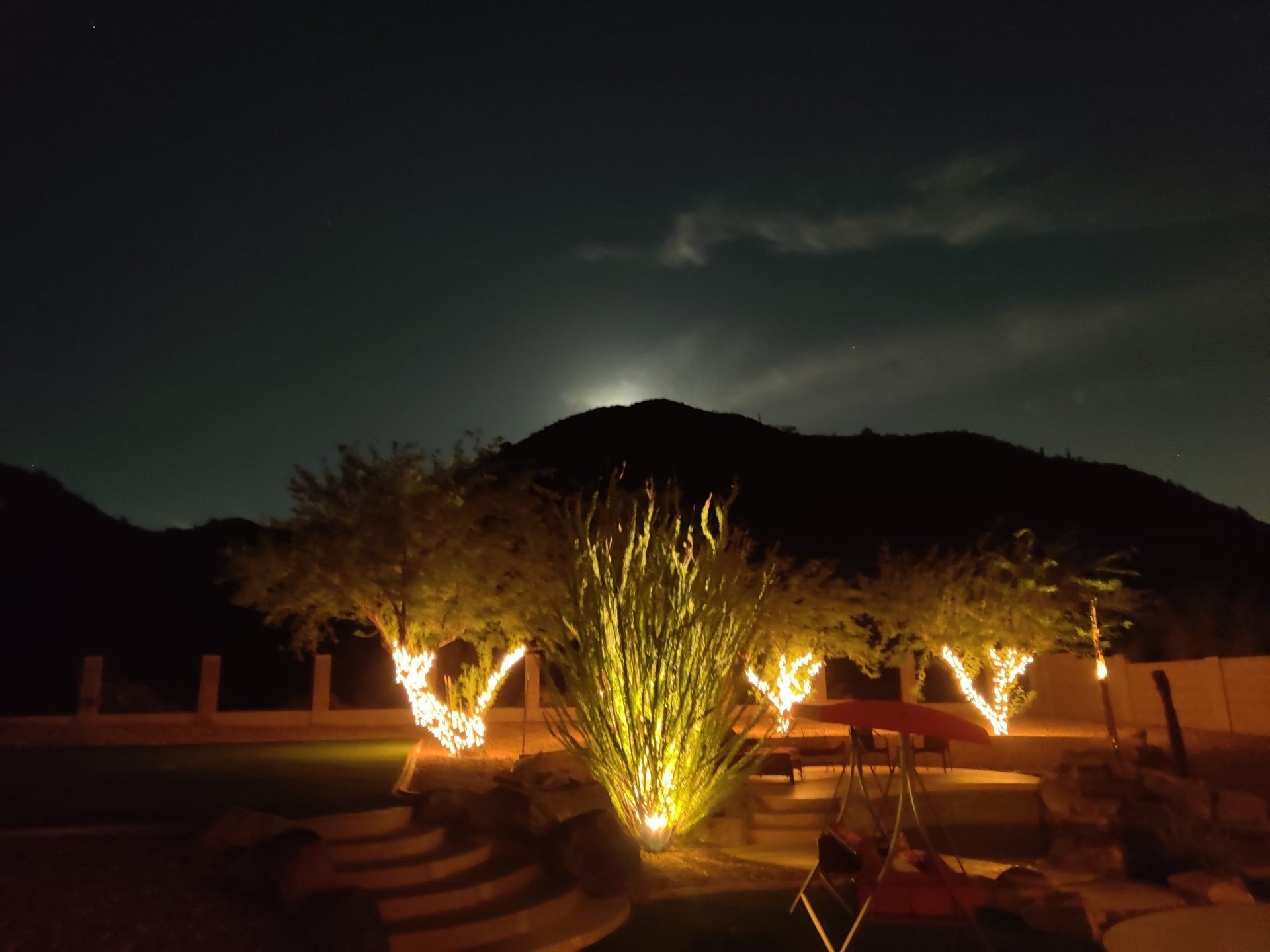 A full moon is visible in the night sky over a backyard