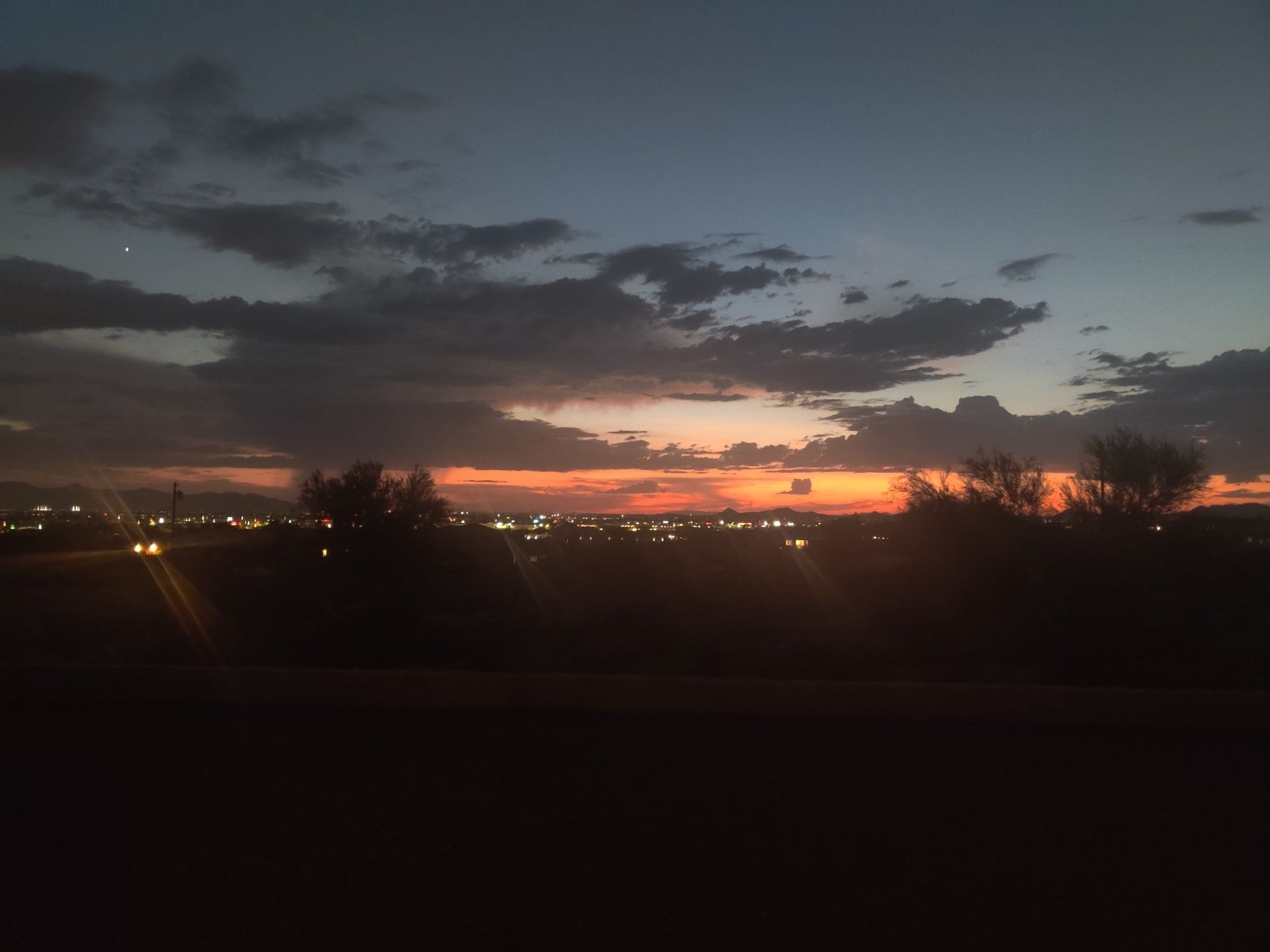 A sunset over a city with trees in the foreground