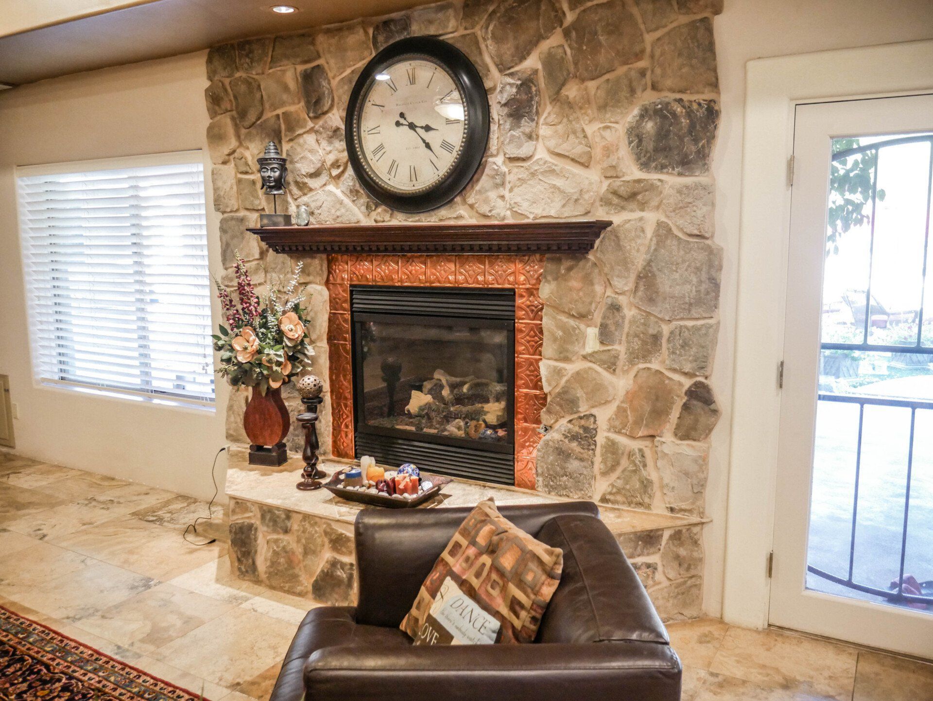 A living room with a fireplace and a clock on the wall.