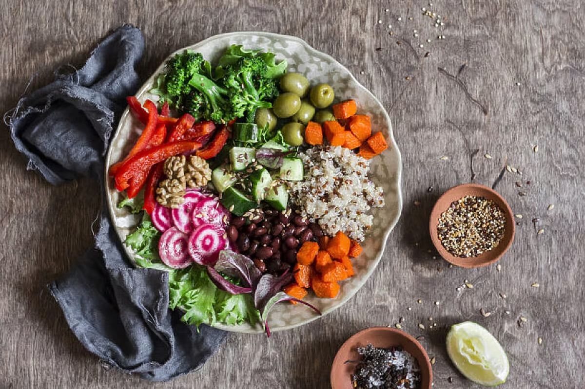Colorful salad bowl with quinoa, greens, olives, tomatoes, and avocado on a rustic table