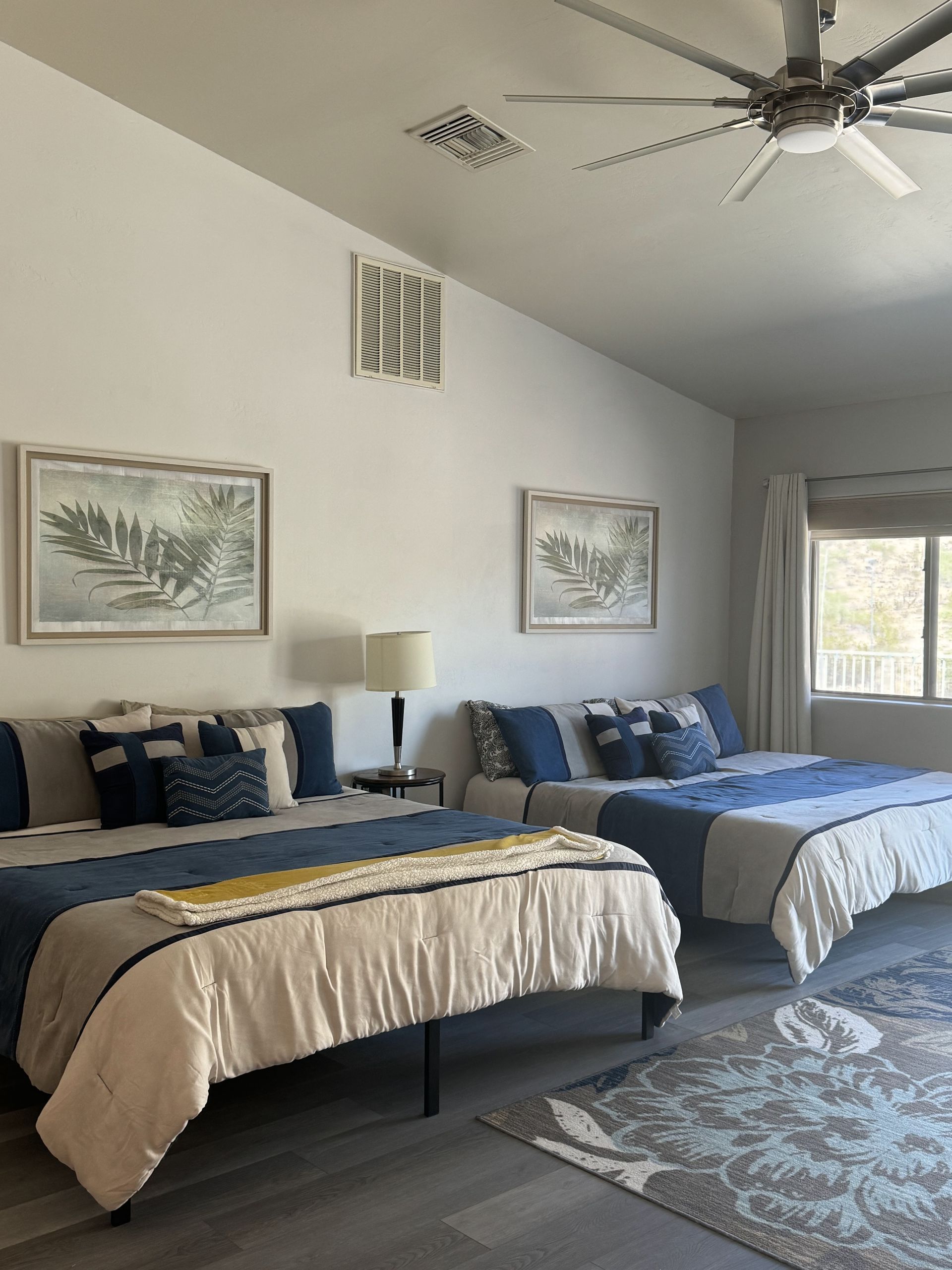 A bedroom with two beds and a ceiling fan.