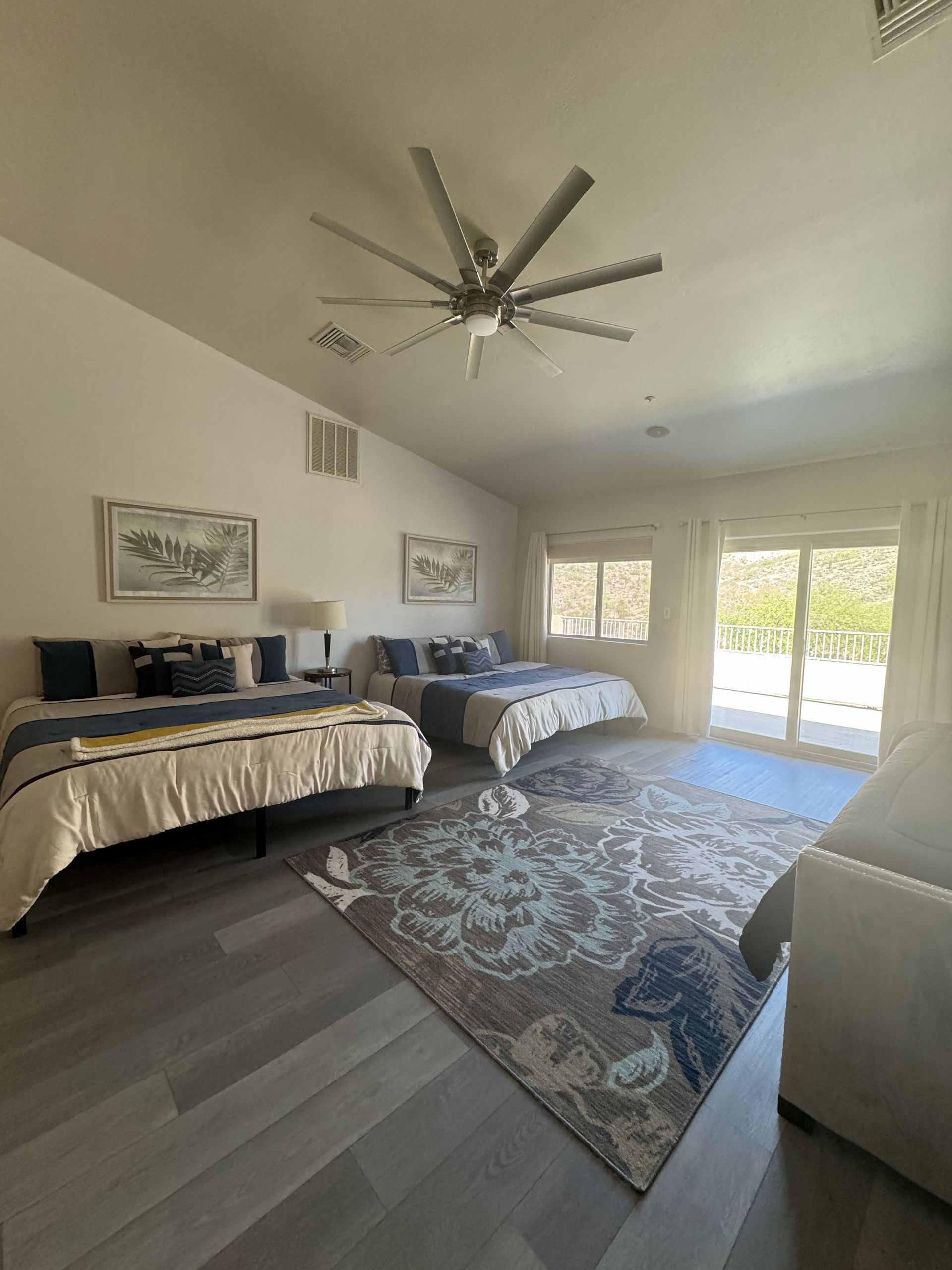 A bedroom with two beds , a couch , and a ceiling fan.