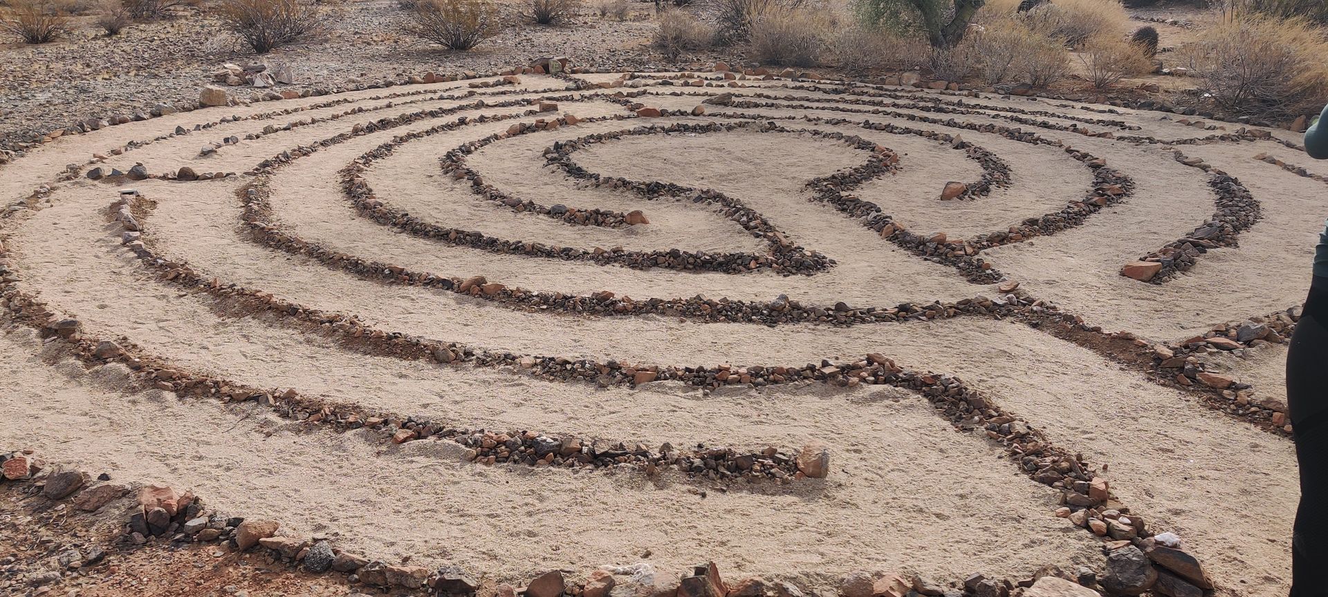 A person is standing in the middle of a labyrinth made of rocks.