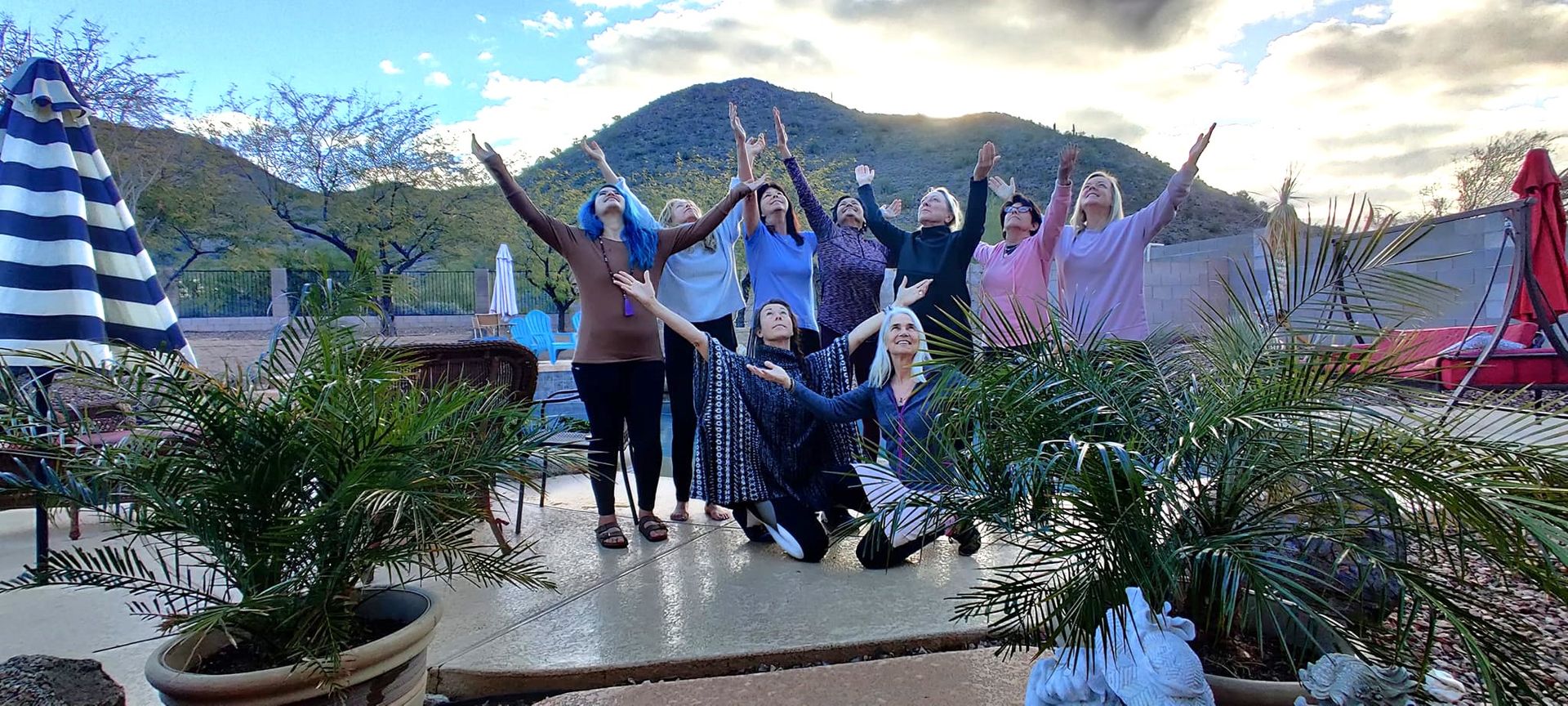 Group of people cheering on a rooftop terrace with mountains and cloudy sky in the background