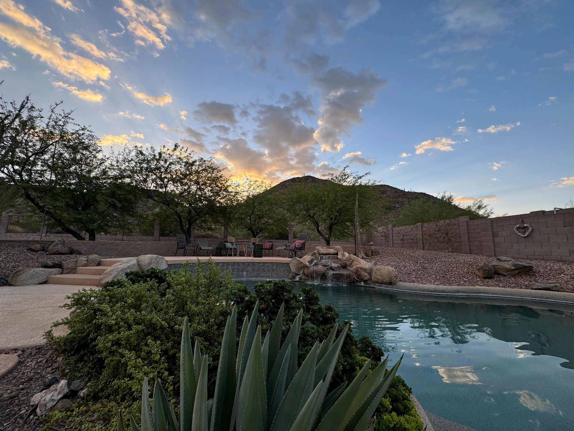 A swimming pool with a mountain in the background at sunset