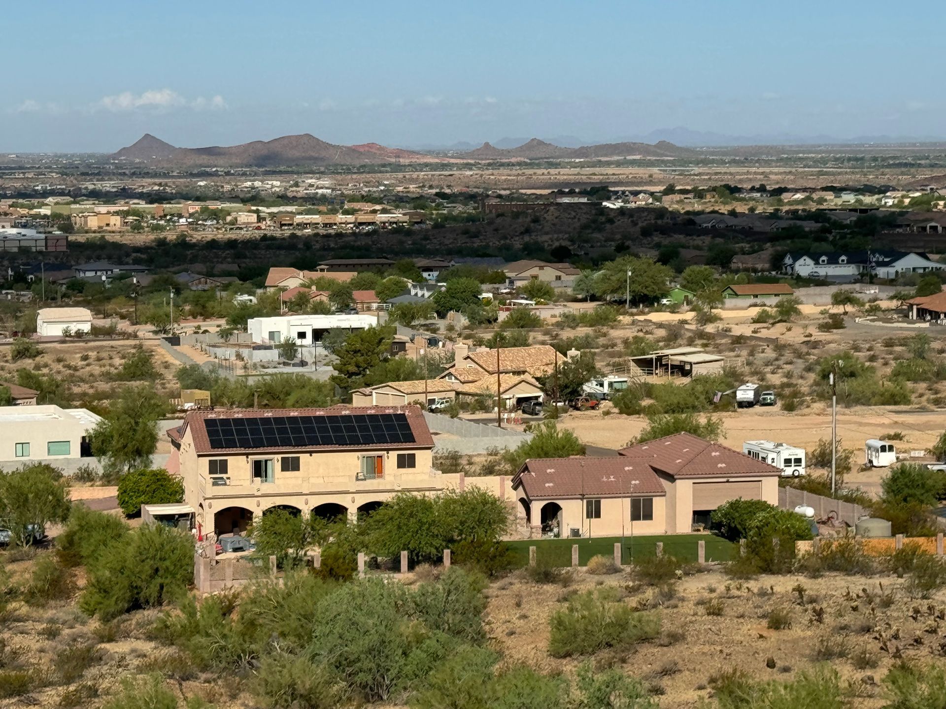 A house with solar panels on the roof is in the middle of a desert landscape.