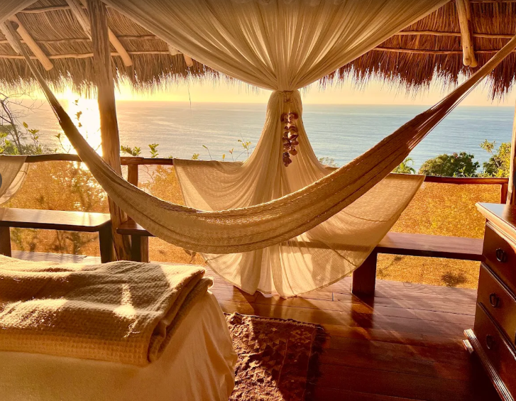 Canopy hammock overlooking a sunny beach and ocean at sunset