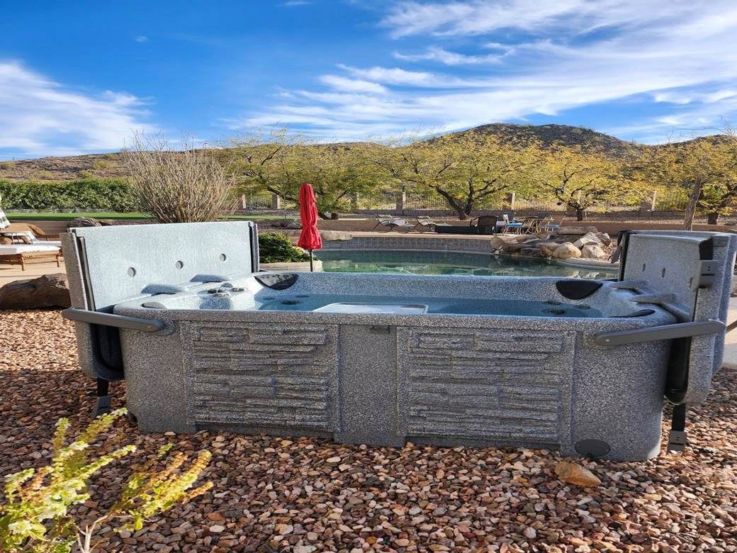 A large hot tub is sitting next to a swimming pool.
