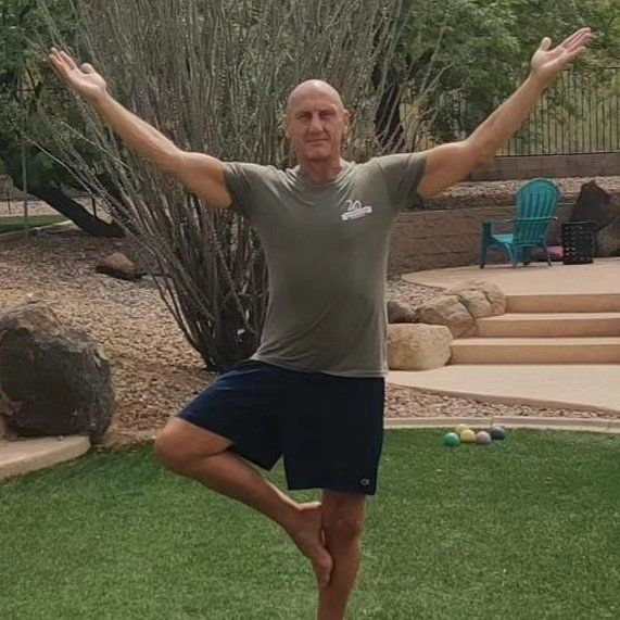 A man is standing on one leg in a yoga pose.