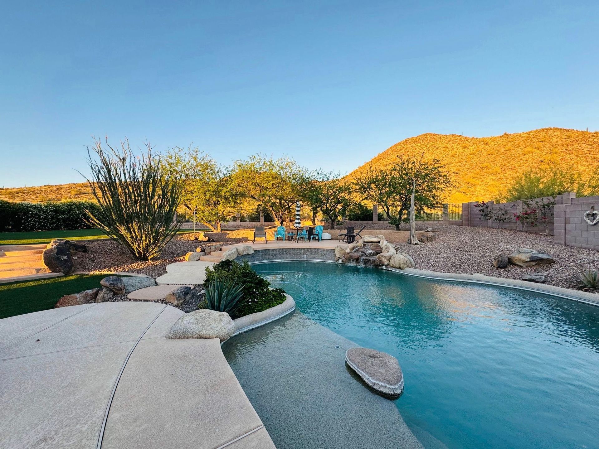 A large swimming pool in the backyard of a house with mountains in the background.