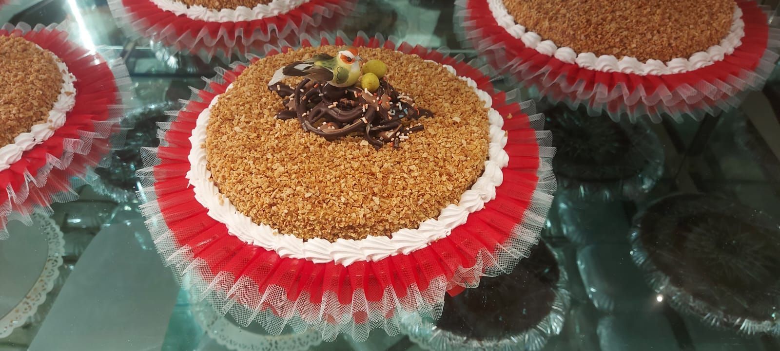 Torte con texture e decorazioni marroni, in pirottini rossi e bianchi, su una superficie di vetro.