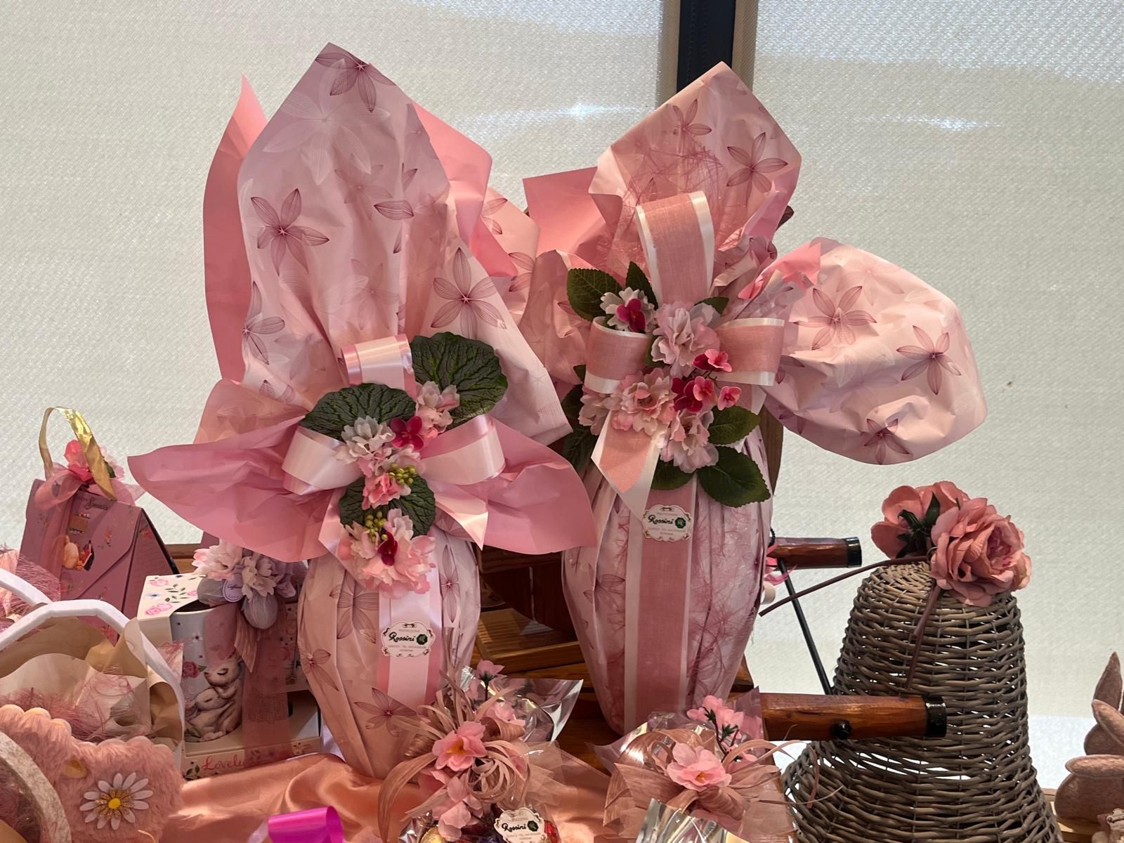 In mostra due grandi regali pasquali rosa a forma di uovo, avvolti in carta e nastri, decorati con fiori.
