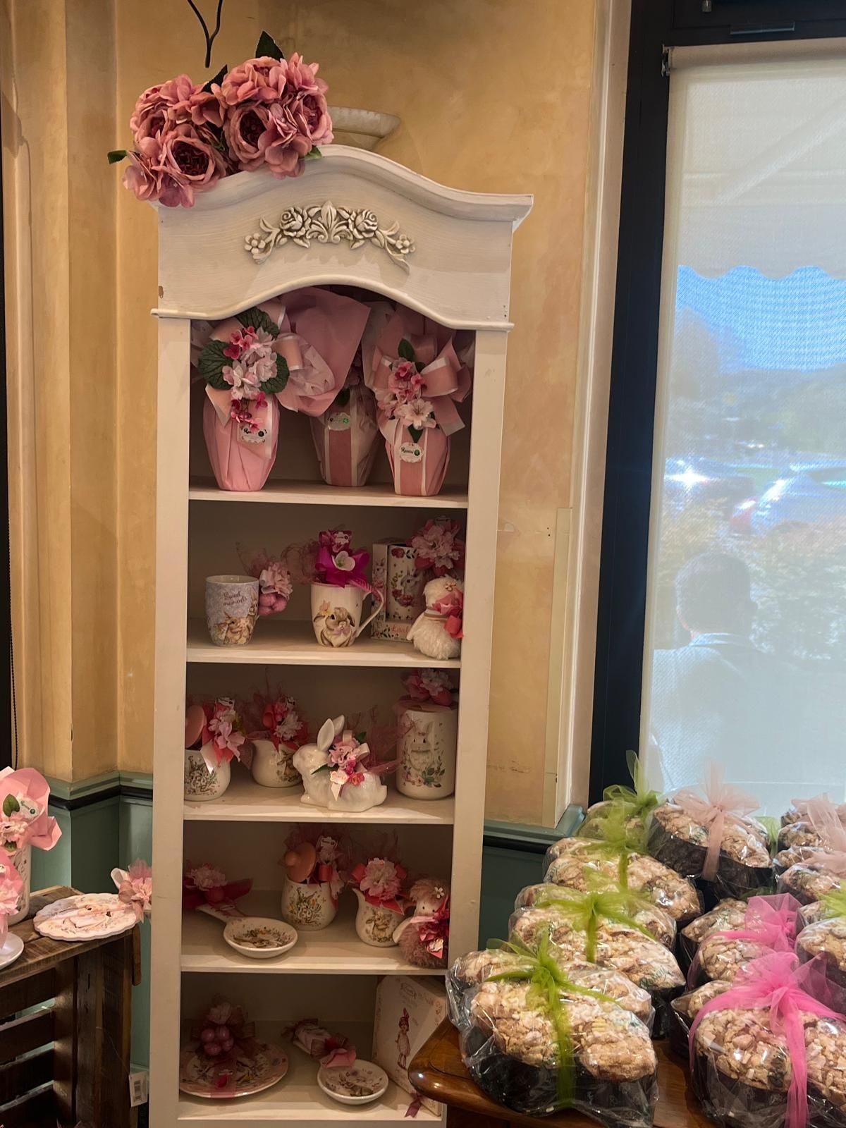 Mensola espositiva bianca con decorazioni rosa e pasticcini.