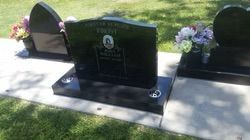 Black granite headstones in a cemetery, with floral arrangements — Mackay Monumental Masons In Glenella, QLD