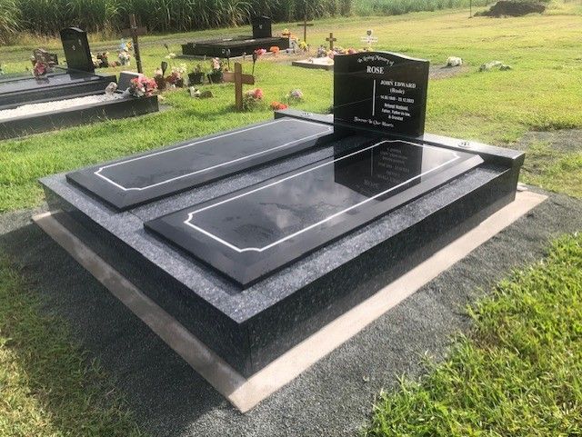 Black granite headstone with curved top in a cemetery.