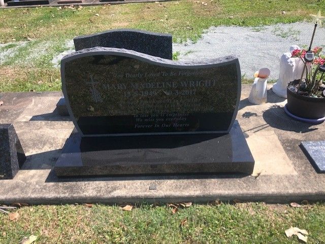 Black granite headstone inscribed with name and dates, in a cemetery.
