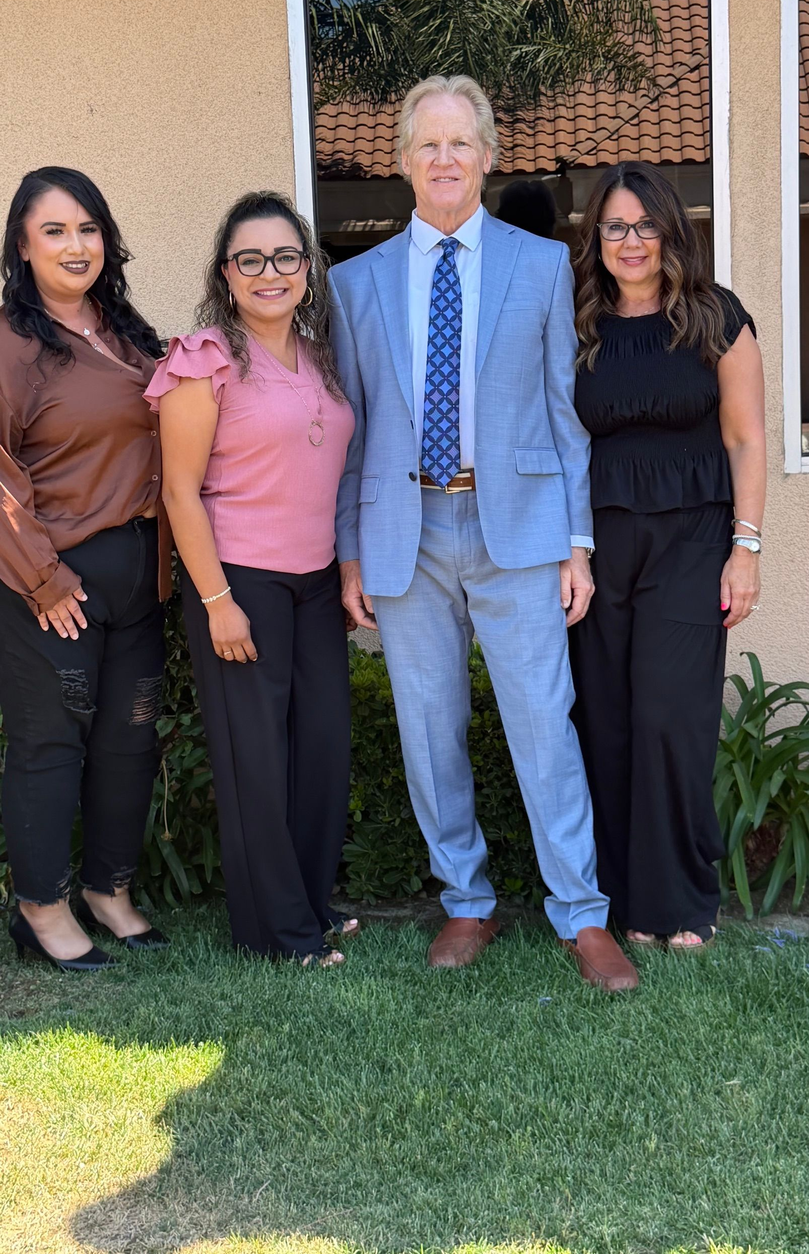 Legal team poses with personal injury attorney outdoors in front of the law office.