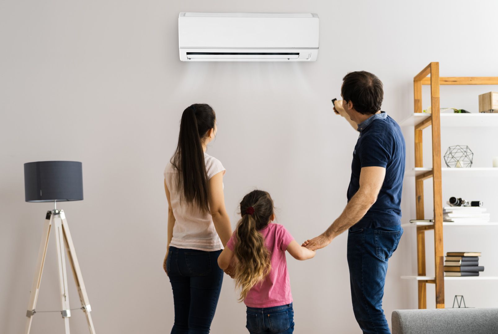 A family is standing in front of a wall mounted air conditioner.