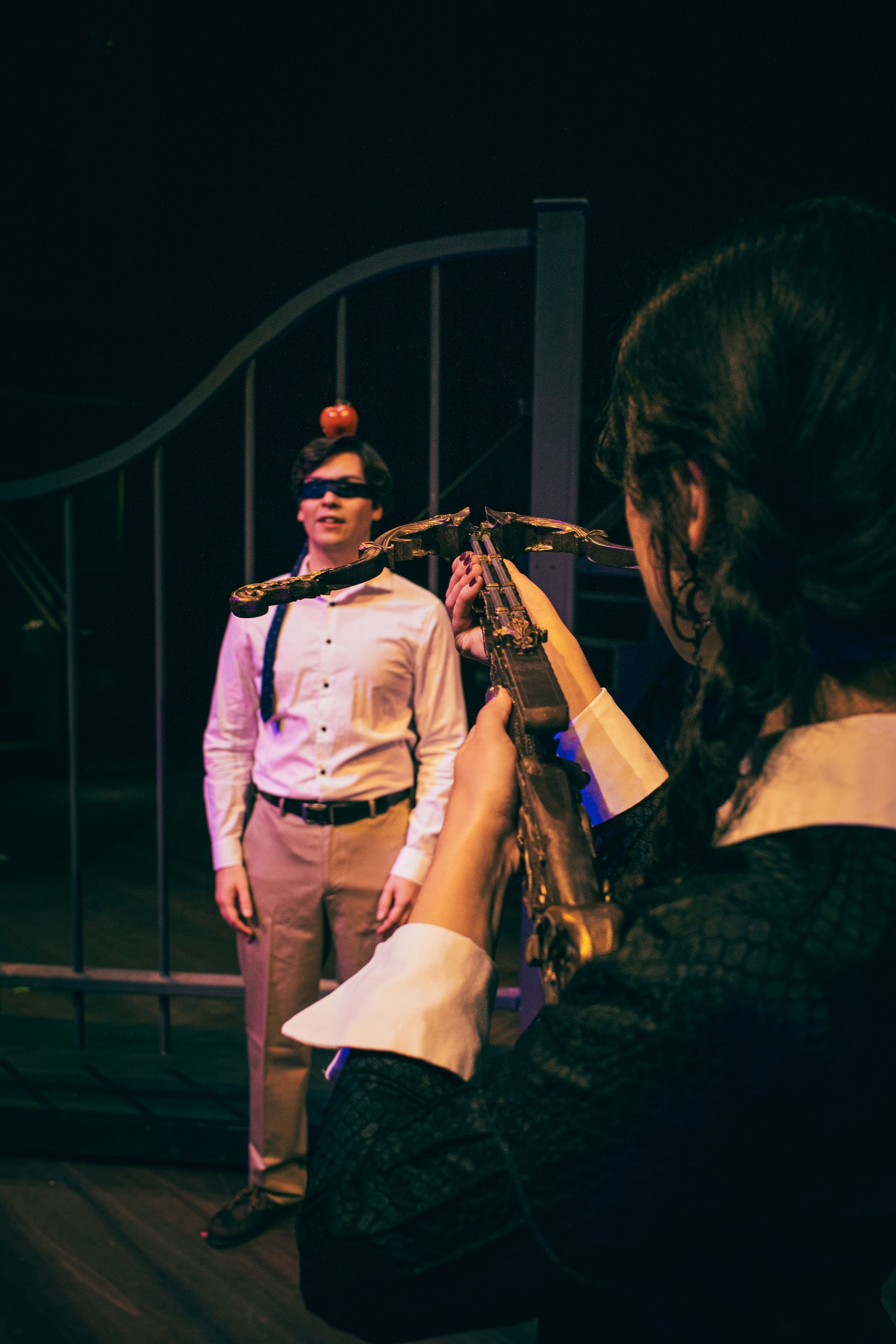 Woman photographing a performer in a white uniform on a dimly lit stage