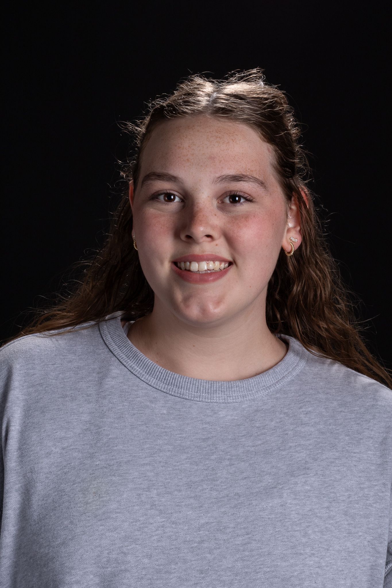Portrait of a smiling person in a gray shirt against a dark background