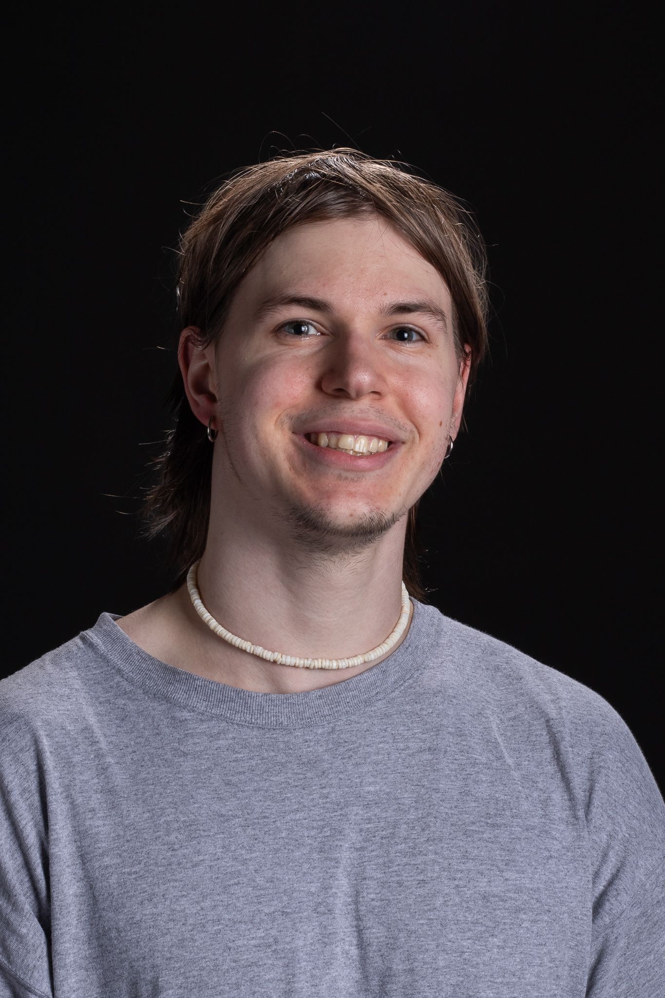 Person smiling in a gray shirt against a dark background