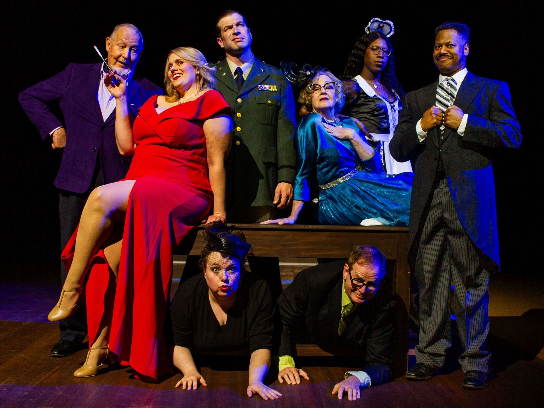Group of costumed actors posing for a play. Various expressions, colors, and costumes on a stage.