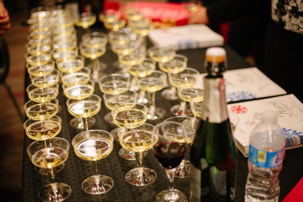 Rows of champagne flutes on a table with a bottle and water, set for a celebration