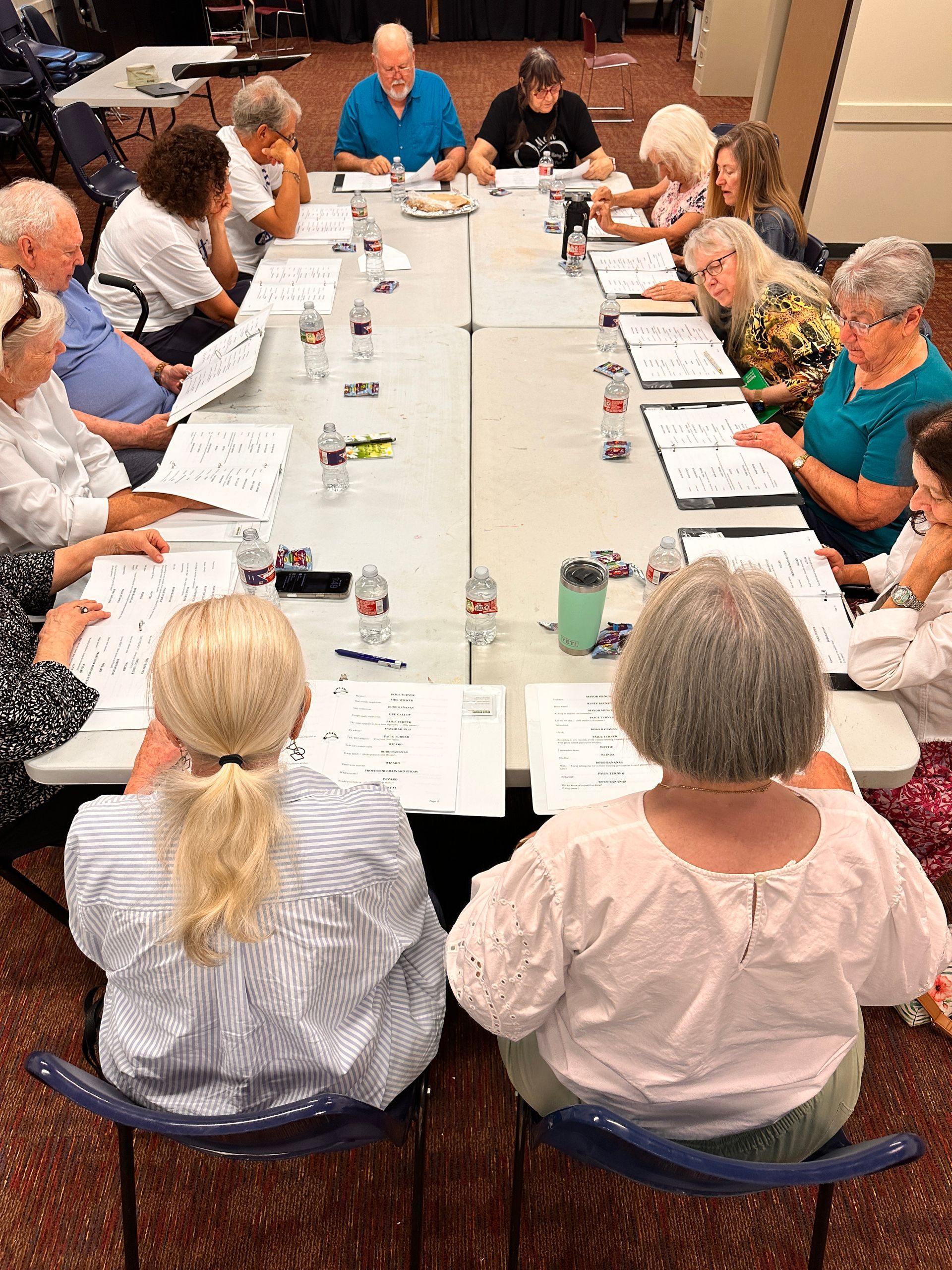 People seated around a long table in a meeting, reviewing papers and notes.