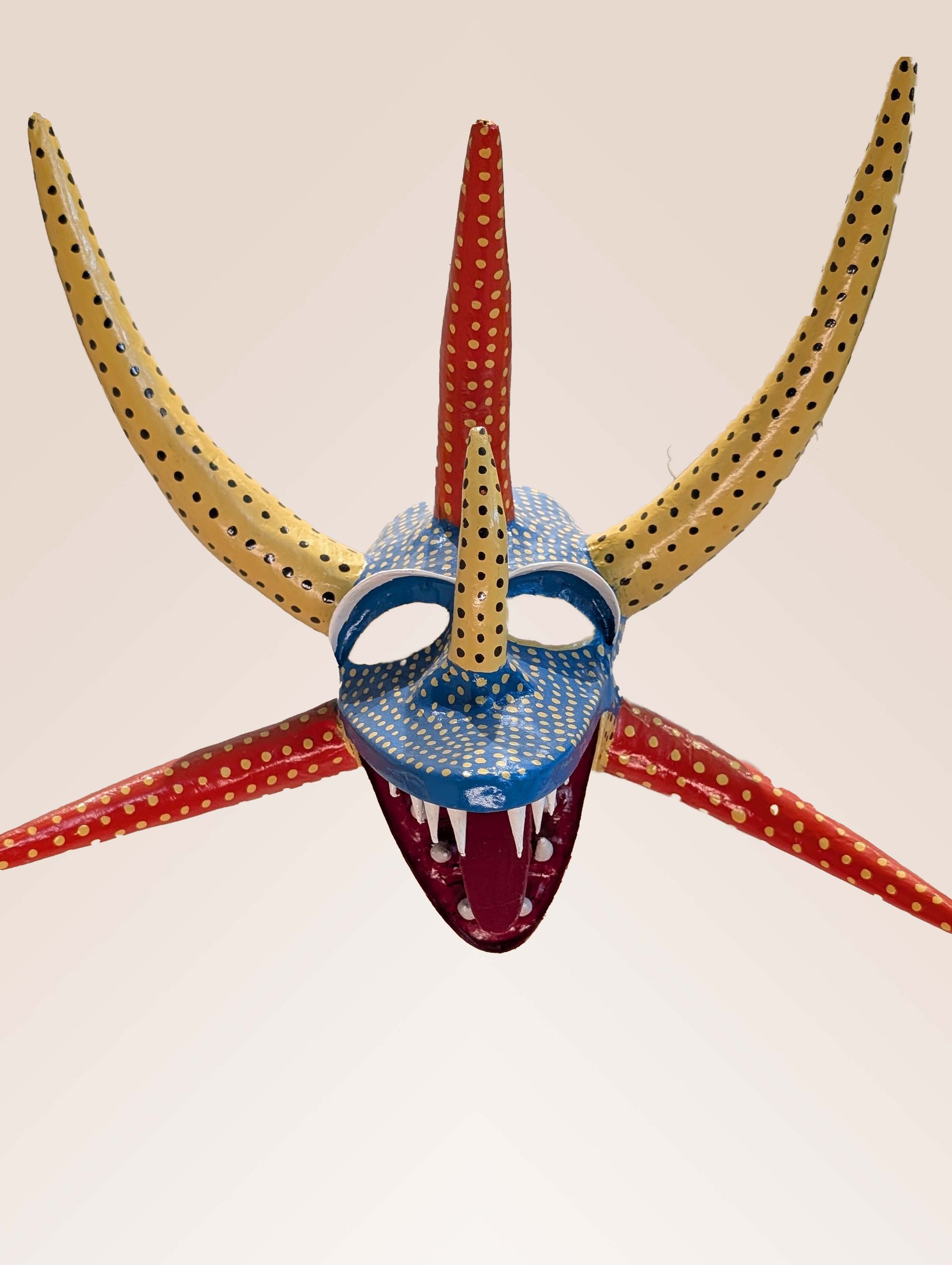 Colorful demon mask with horns and sharp teeth.